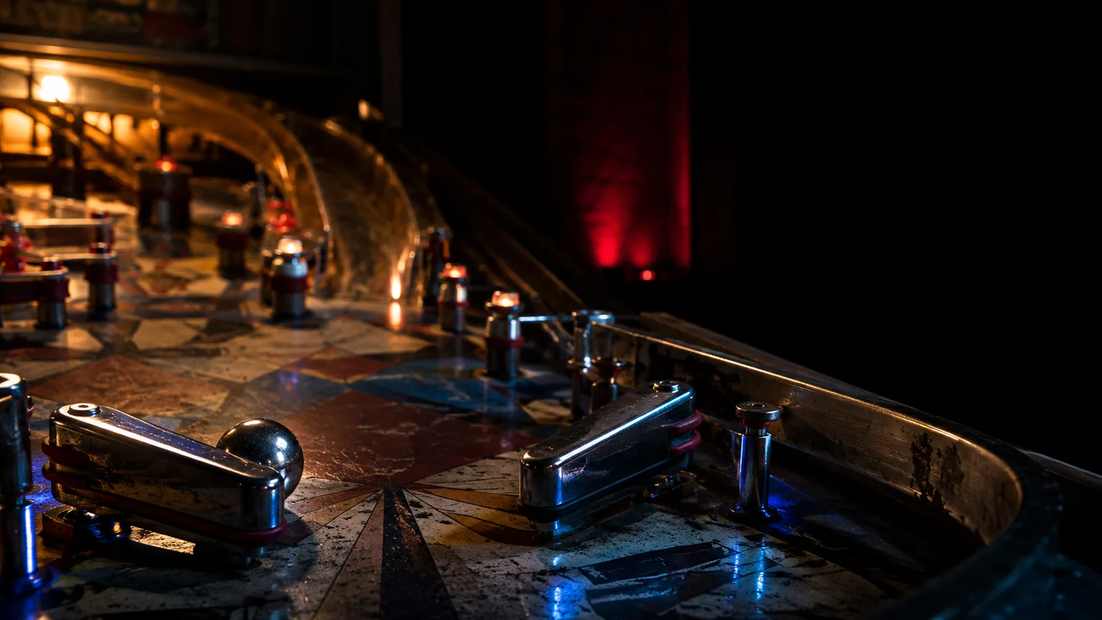 Chrome flippers and a steel ball on a worn pinball playfield